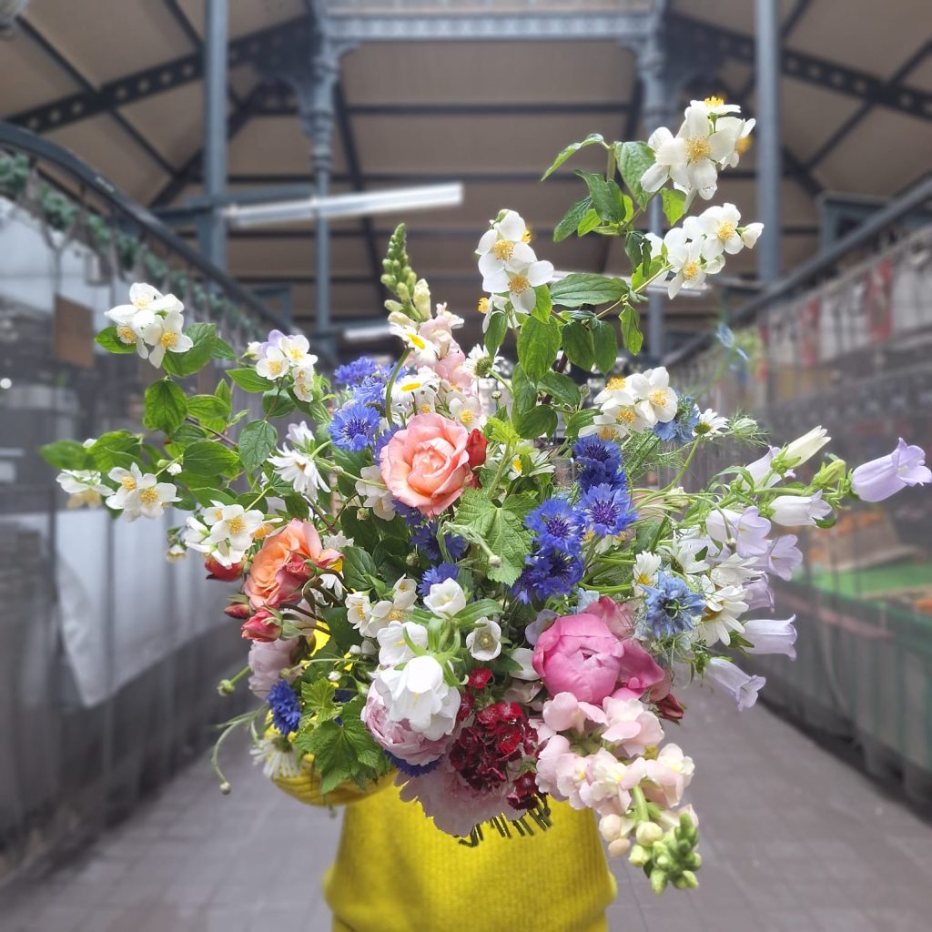 Grand bouquet de fleurs de saison dans un vase jaune au stand Sens Fleuriste Caviste
