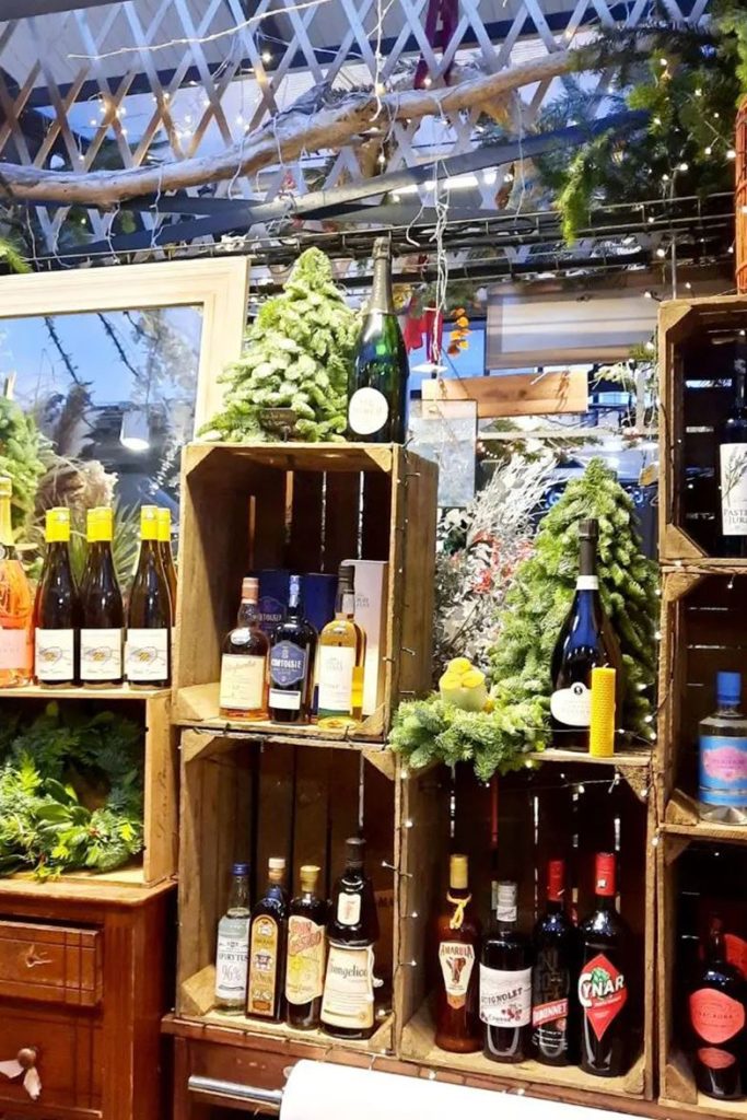Les caisses de vin et les plantes du stand Sens Fleuriste Caviste au marché couvert