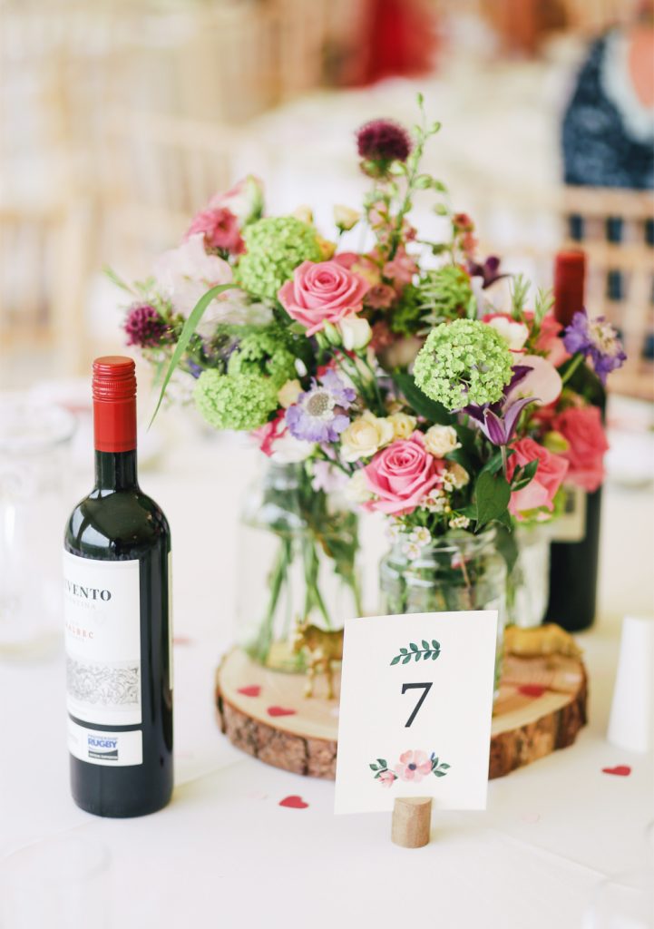 Bouteille de vin rouge et bouquet de fleurs de saison sur une table dressée pour un dîner