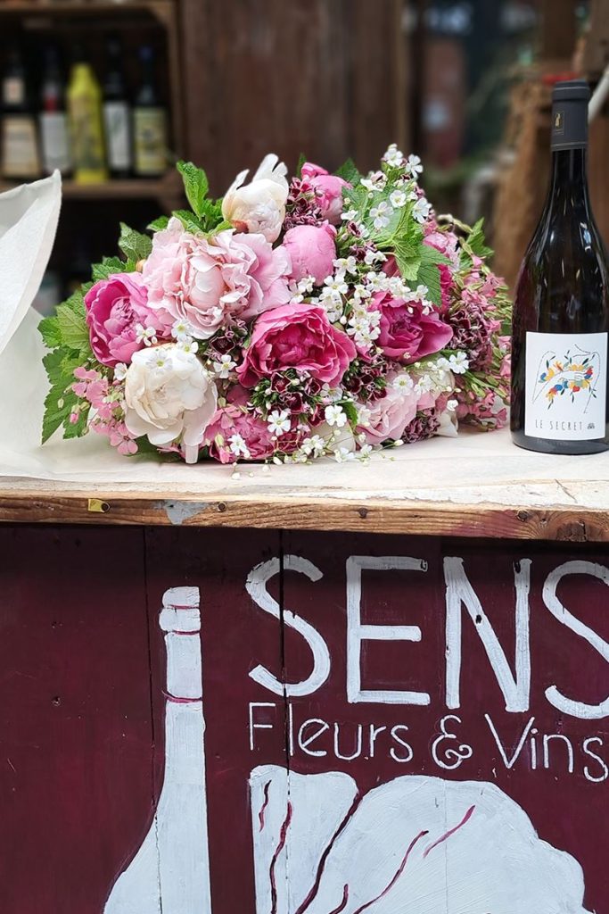 Le stand Sens Fleurs et Vins au marché couvert de la rue de l’Olive, un bouquet et une bouteille