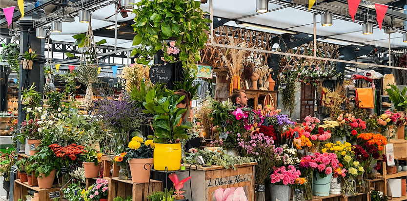 Le stand fleuri de Sens Fleuriste Caviste sous la halle du marché de la rue de l’Olive